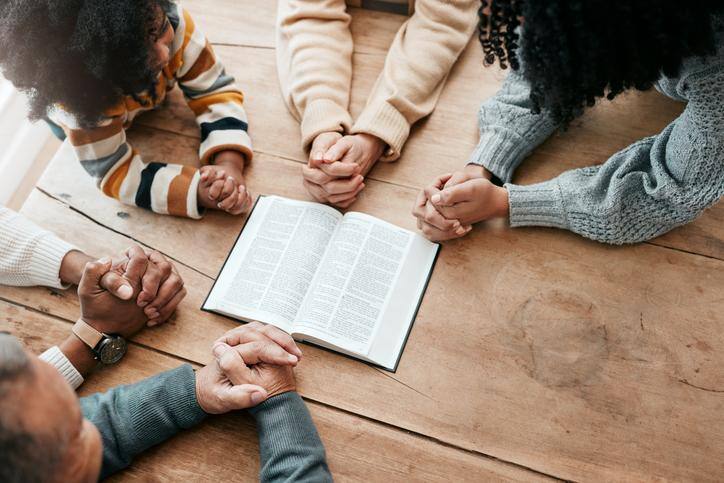 Christians gathered around bible praying together